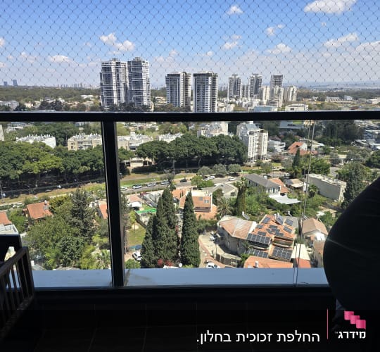 נוף עירוני עם מרפסת זכוכית ורשת בטיחות